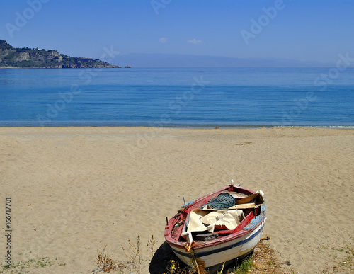 Empty sandy beach with abandoned boat