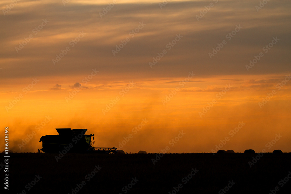 Mähdrescher bei der Ernte zum Sonnenuntergang Mähdrescher bei der Ernte zum Sonnenuntergang