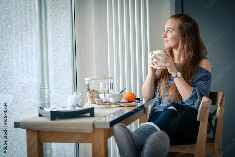 Junge Frau beim Frühstück am Fenster