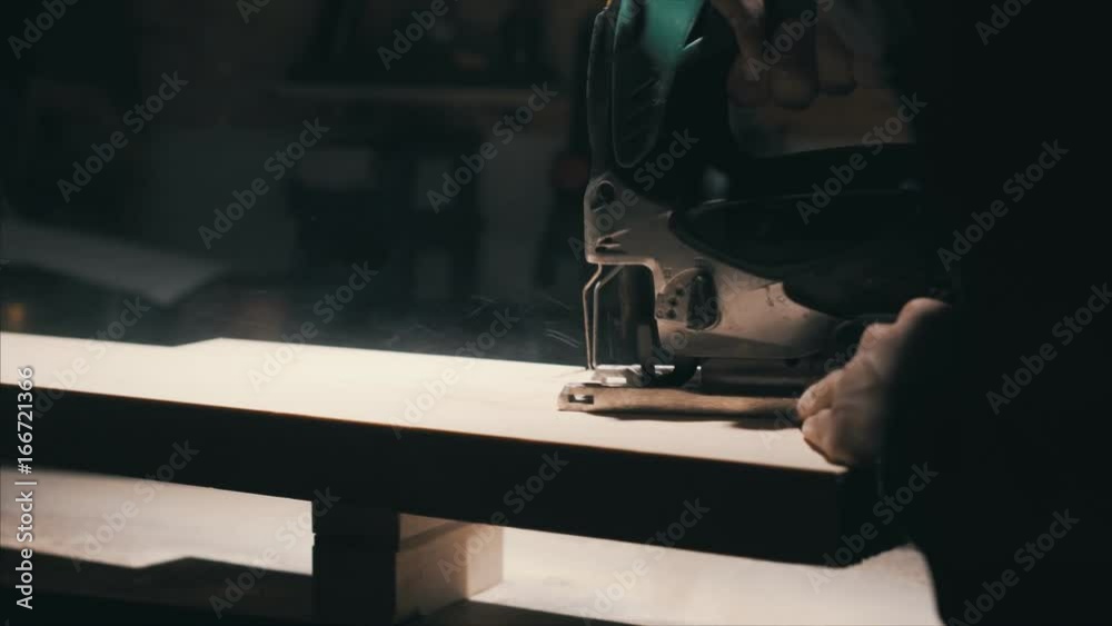 Close-up electric jigsaw cutting a piece of wood, a thick piece of wood , lowlight Close-up electric jigsaw cutting a piece of wood, a thick piece of wood , lowlight