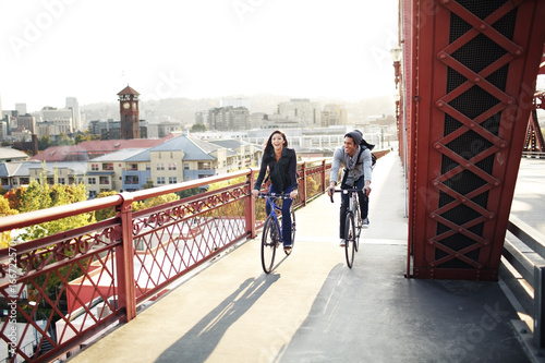 Two people riding bikes across bridge in the evening
