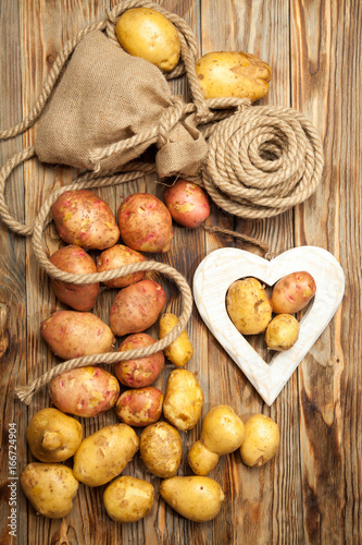 Potatoes, bag with rope, heart on a wooden background
