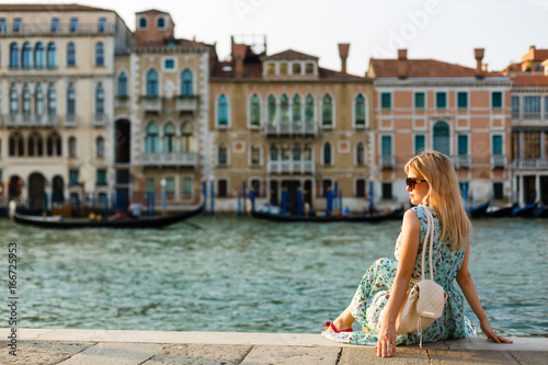 girl sitting on a pier near the canal at the venice. Italy © Angelov