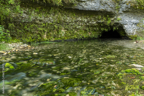 Fototapeta Naklejka Na Ścianę i Meble -  Big Spring Cave - A spring flowing out of a cave during summer.
