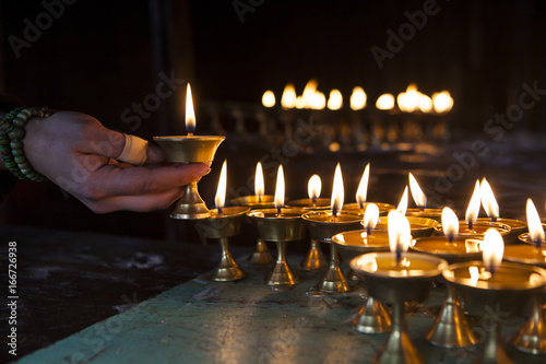 Hand of a traveller lighting a butterlamp.