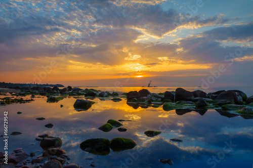 Sunset over the sea, stones at foreground