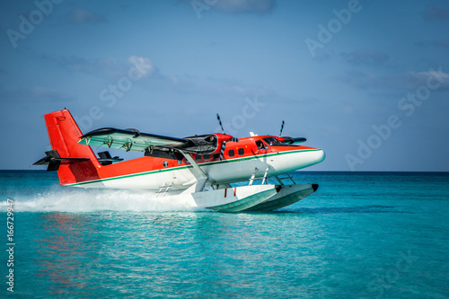 Landing seaplane in the ocean lagoon. The takeoff of a seaplane at ocean beach. photo