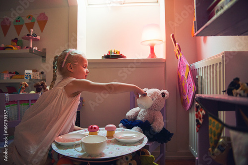 Tableau sur toile Girl playing tea-party with her toy bear