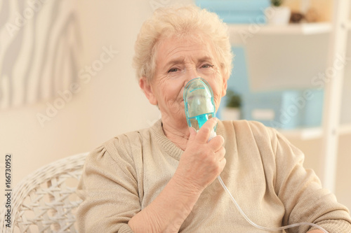Elderly woman using asthma machine at home