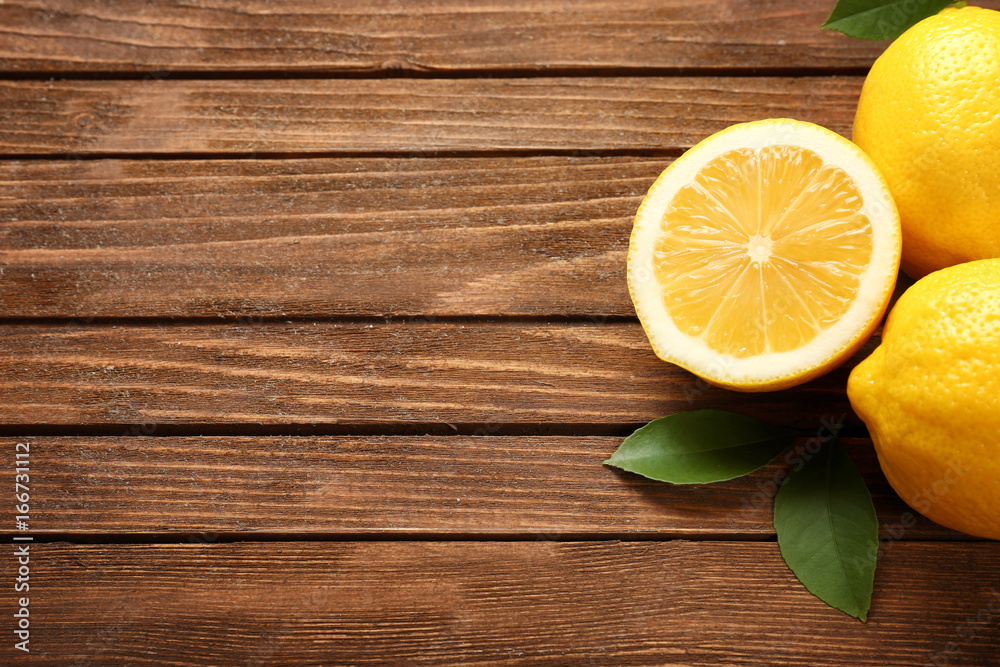 Delicious fresh lemons with green leaves on wooden table Delicious fresh lemons with green leaves on wooden table