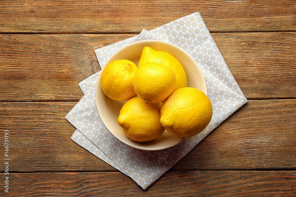 Bowl with delicious lemons on wooden table