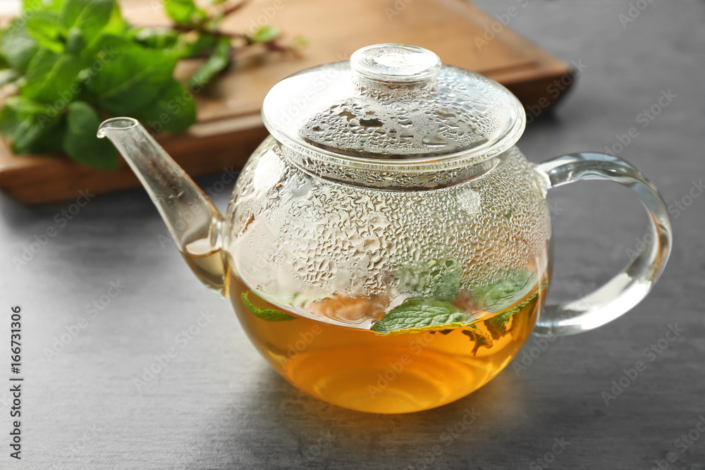 Glass teapot with hot tasty lemon balm tea on table Glass teapot with hot tasty lemon balm tea on table