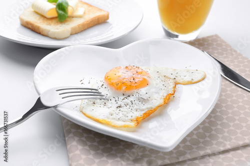 Cutlery and plate with over hard fried egg on light table