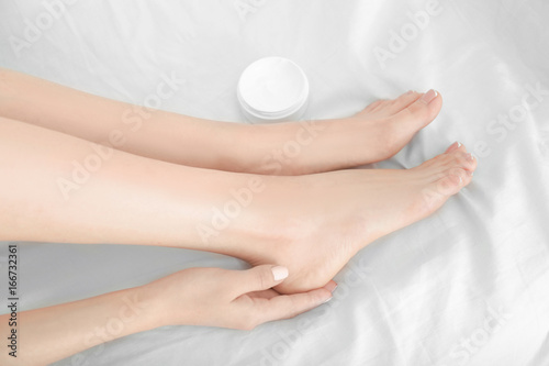Woman applying cream onto her feet, closeup