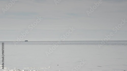 Boat travels on water in distance, wide