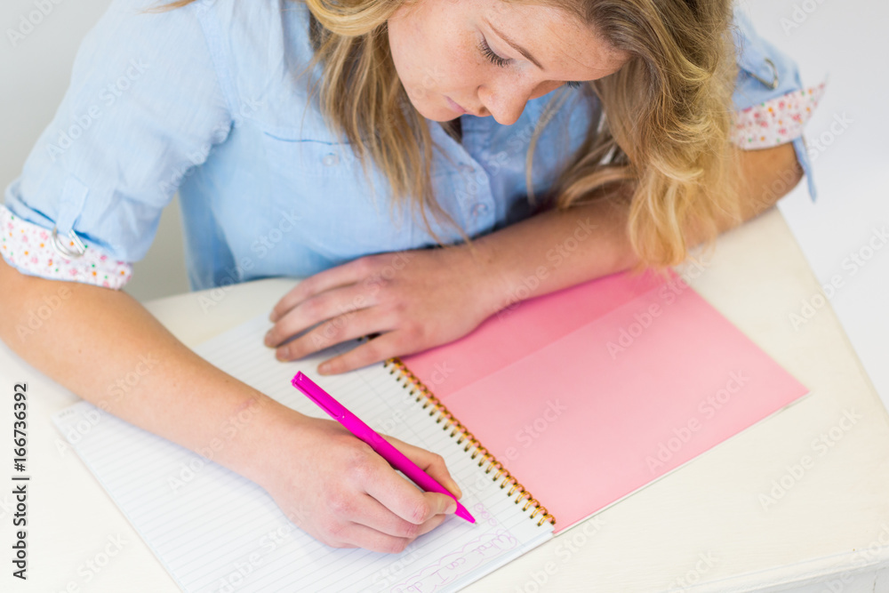 Student girl deciding about her future career sitting at desk with pink notebook and pen. Student girl deciding about her future career sitting at desk with pink notebook and pen.