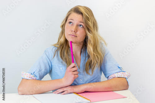 Εκτύπωση καμβά Student girl deciding about her future career sitting at desk with pink notebook and pen thinking