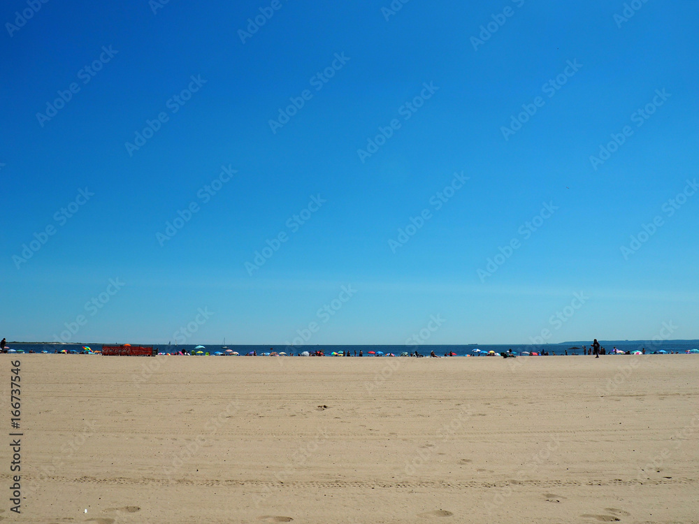 Sandy beach with umbrellas and people in the distance Sandy beach with umbrellas and people in the distance