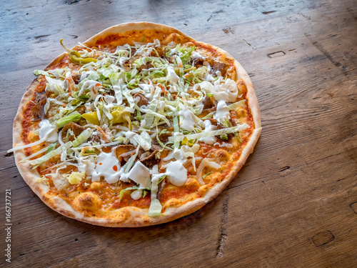 Kebabpizza with Garlic sauce on wood table. Swedish pizza style.