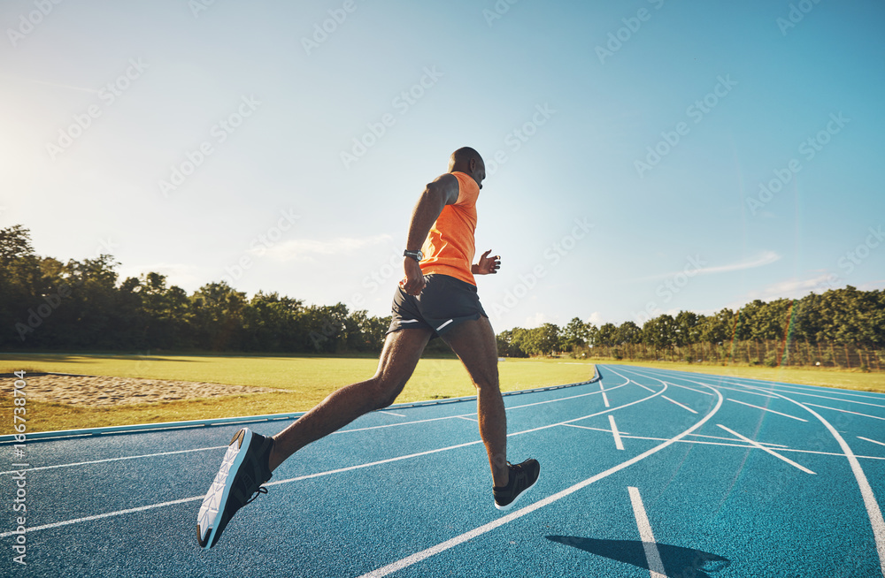 Fit athlete sprinting alone down a running track outside