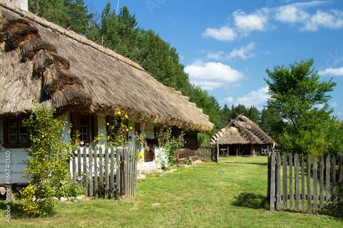 Obraz na płótnie Rural landscape with a cozy old cottage, fence, flowers and an animal farm w salonie