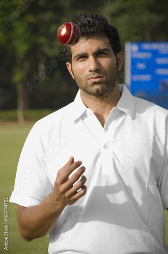 Bowler tossing cricket ball in air 