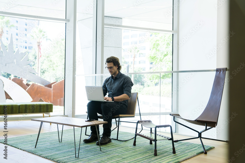 Hip man working on laptop in a modern tech business office Hip man working on laptop in a modern tech business office