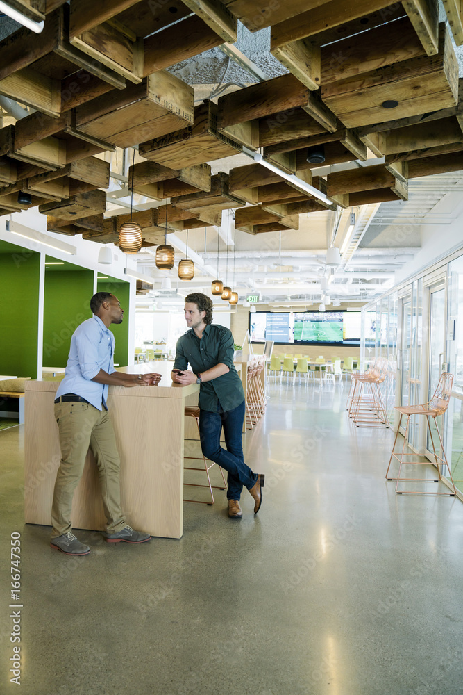 Two co-workers meeting in common area of modern office space