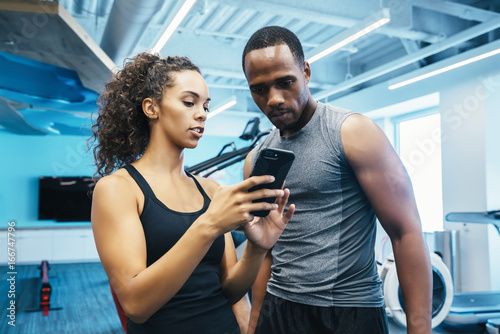 Man and woman looking at a cell phone in the gym 