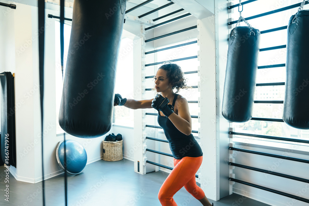 Woman hitting boxing bag in gym 