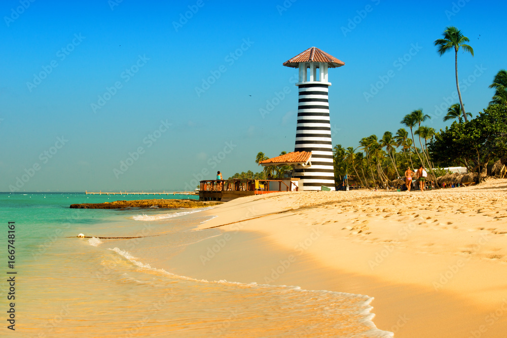 Obraz premium Striped red white lighthouse on the coast of the Caribbean Sea. Dominican Republic.