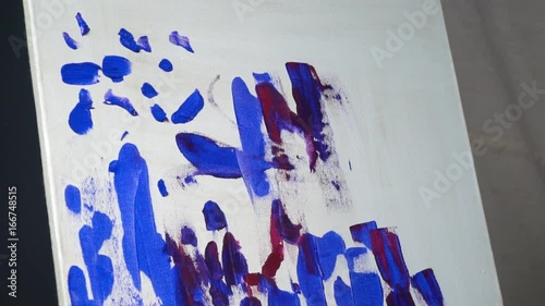 Female hands smeared in paint make brush blue strokes on canvas photo