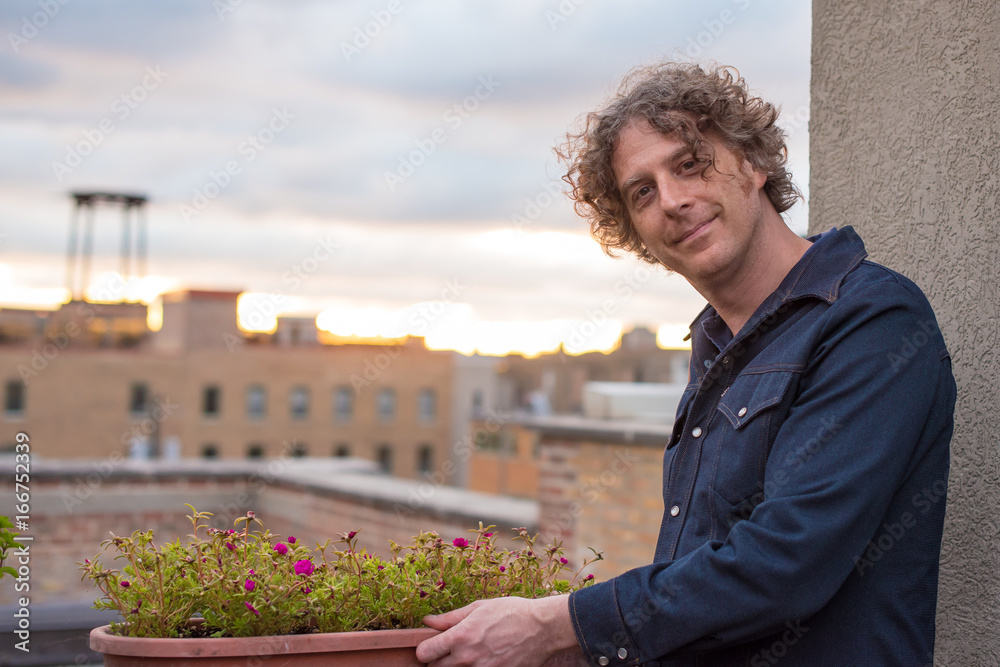 Attractive forty something man gardening on a rooftop in the city Attractive forty something man gardening on a rooftop in the city