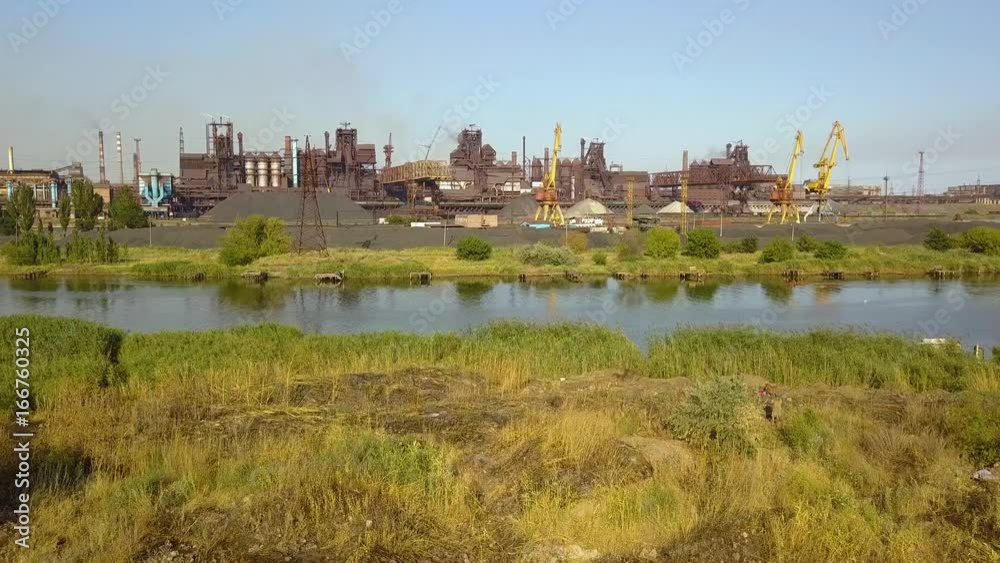 Blast furnace view from the air. Old factory. Aerial view over industrialized city with air atmosphere and river water pollution from metallurgical plant near sea. Blast furnace view from the air. Old factory. Aerial view over industrialized city with air atmosphere and river water pollution from metallurgical plant near sea.