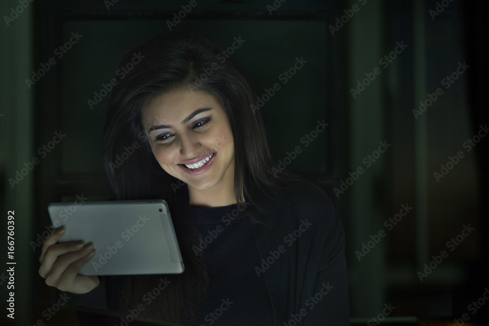 Smiling woman using digital tablet at night Smiling woman using digital tablet at night