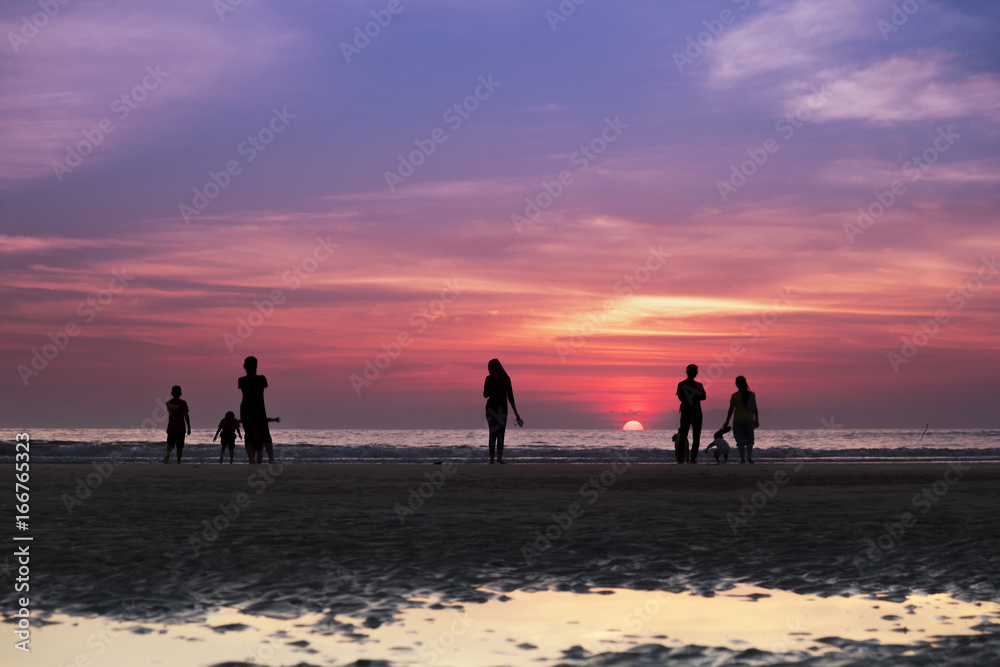A group of people watching the sun setting over the horizon with beautiful twilight in the background