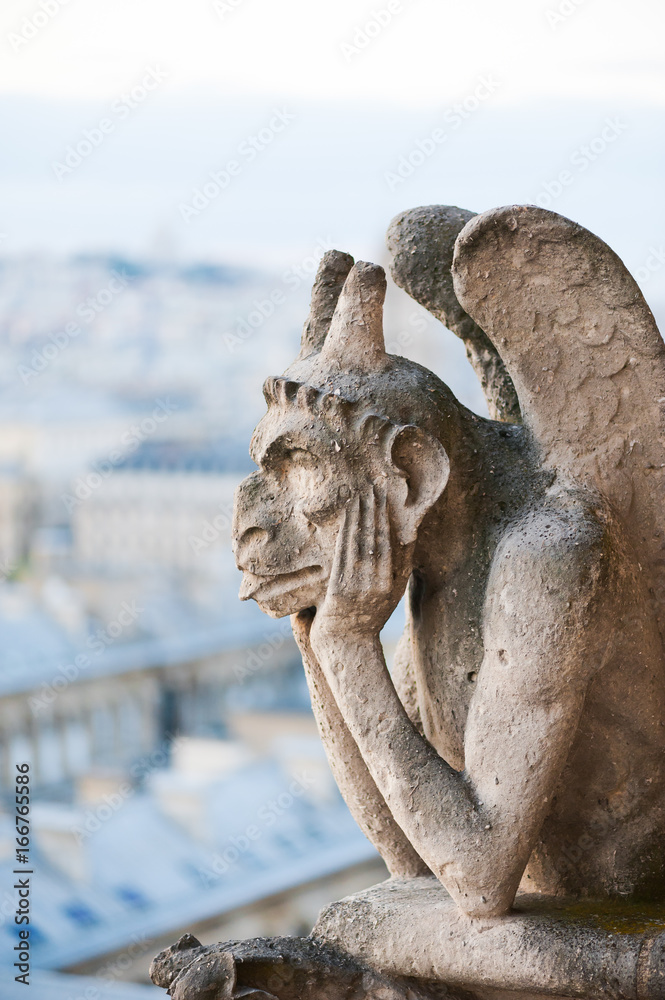 Gargoyle on a Paris roof with the city in the background, France