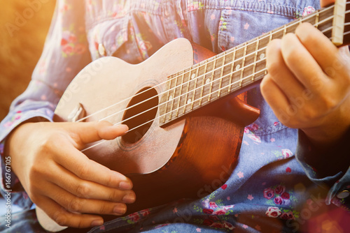 Tableau sur toile Close-up of little hipster girl playing ukulele guitar, vintage film tone effect
