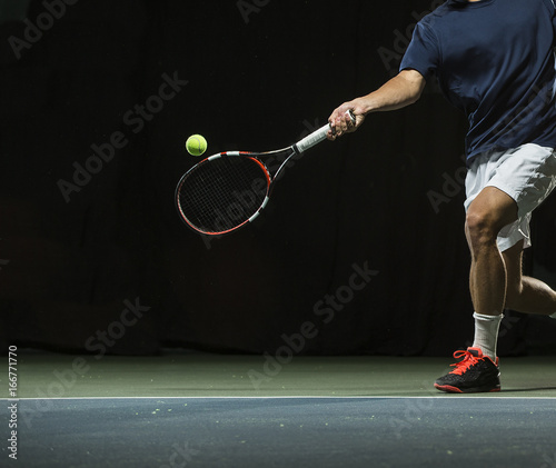 Close up photo of a man swinging a tennis racquet during a tennis match