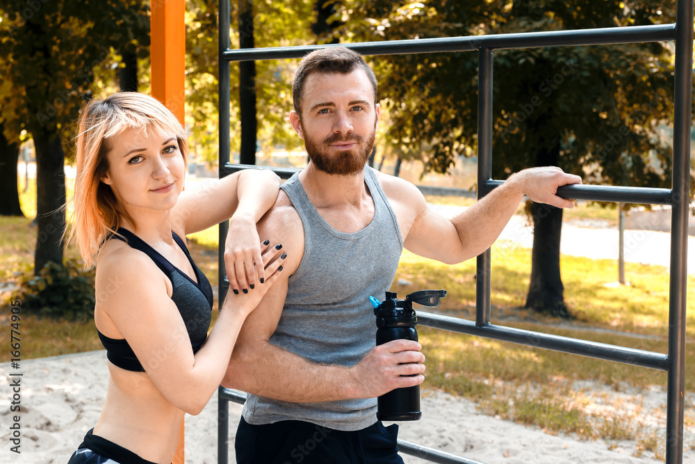 Obraz premium Sporty blonde girl and bearded man is resting after workout training in a park at autumn day.