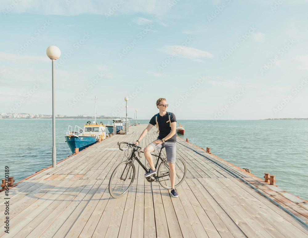 Man standing with bicycle on the pier.