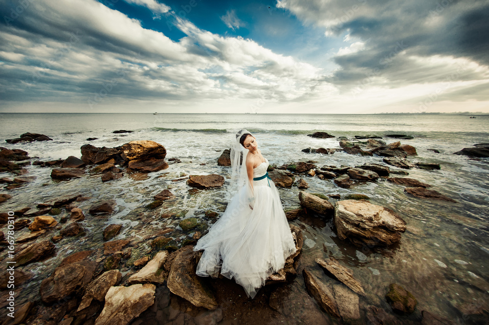 Bride with a long veil for a walk by the sea Bride with a long veil for a walk by the sea