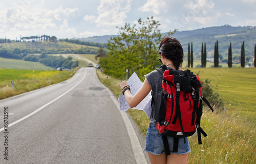 Young woman traveling with paper map in the green field