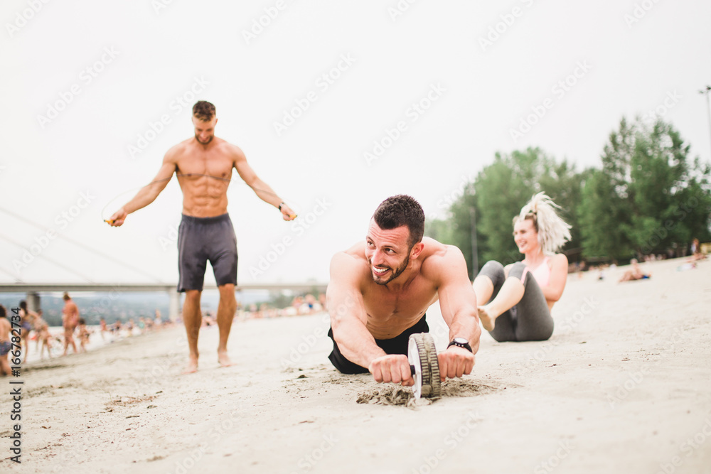 Group young attractive people having fun on beach and doing some fitness workout. 