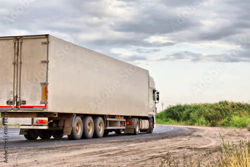 white lorry with white trailer over blue sky on the road