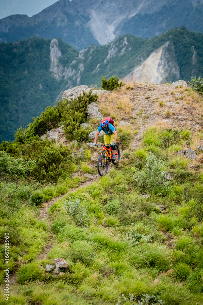 Colourful Mountain biker in big mountains Tuscany