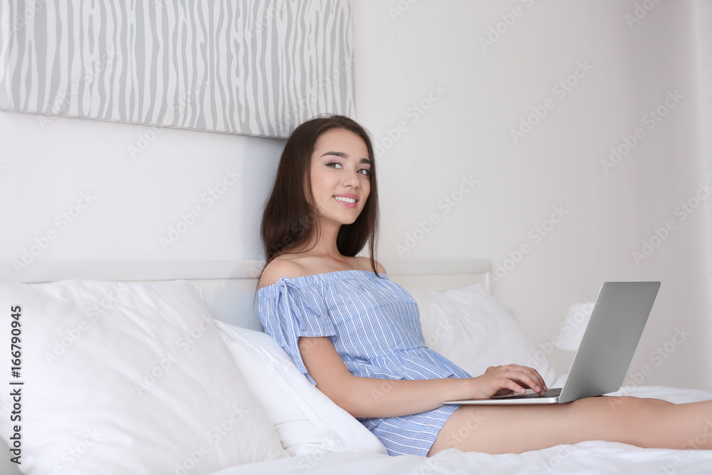 Young beautiful woman using laptop on bed in light hotel room Young beautiful woman using laptop on bed in light hotel room