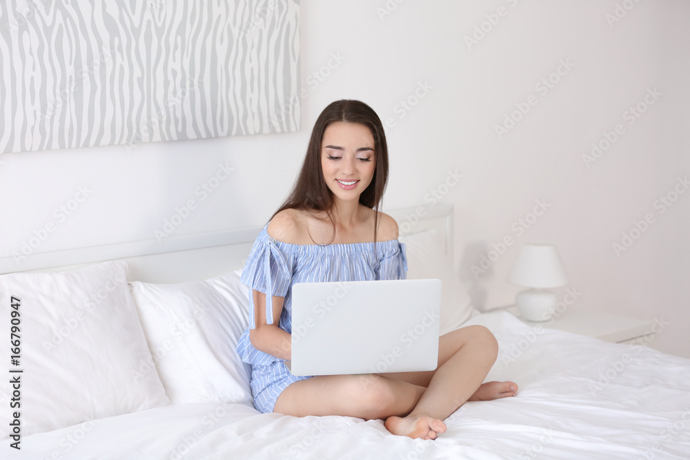 Young beautiful woman using laptop on bed in light hotel room Young beautiful woman using laptop on bed in light hotel room