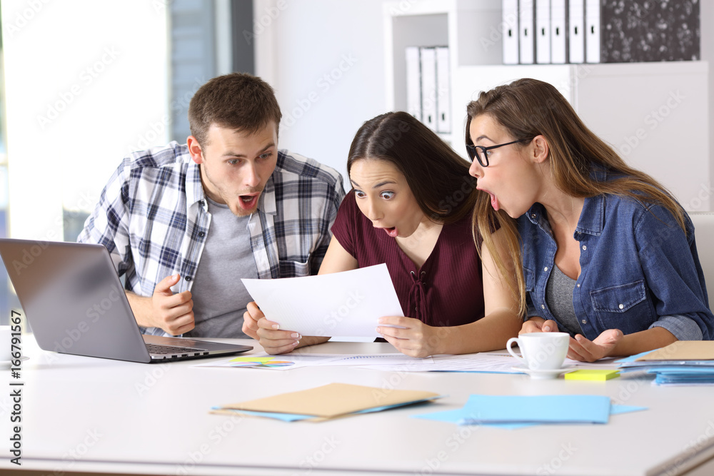 Amazed employees reading a document at office Amazed employees reading a document at office