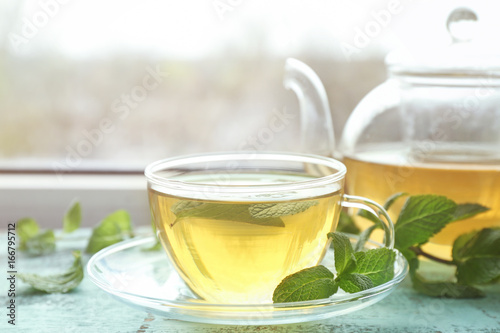 Cup of hot aromatic tea with lemon balm on window sill
